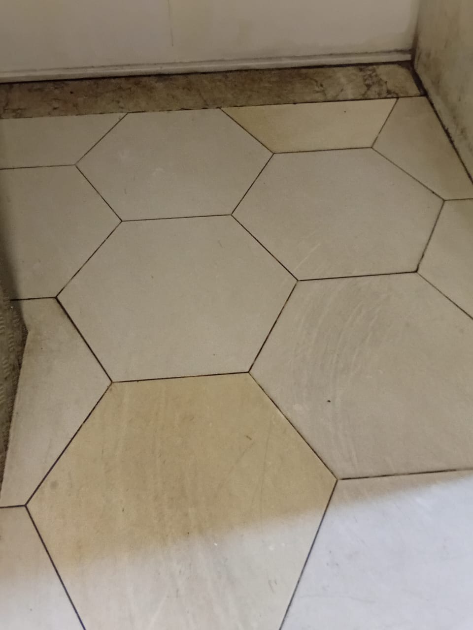 Piso hexagonal do hall de entrada antes da limpeza, com rejunte escurecido