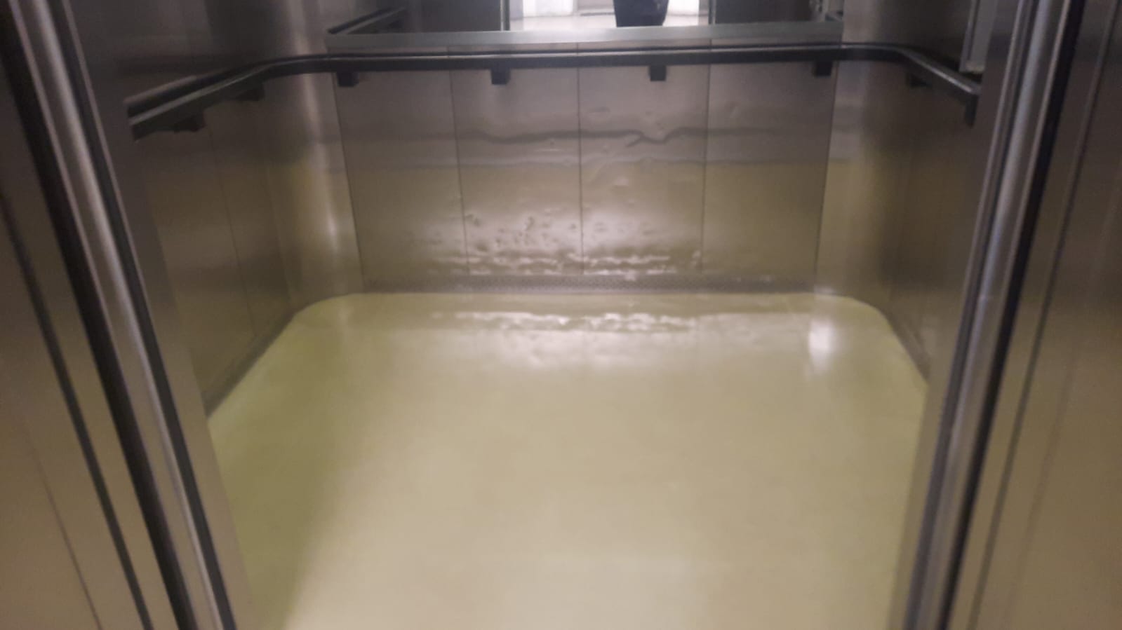 Piso do elevador antes da limpeza, com sujeira e resíduo amarelado